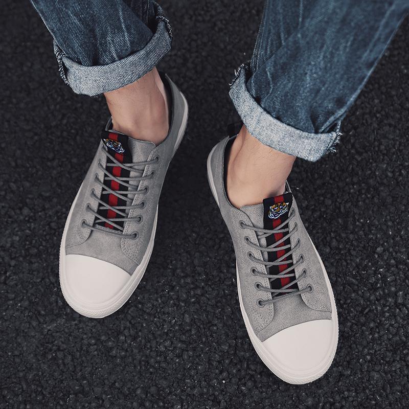 Gray low-top sneakers with red lace accents and white rubber toe caps