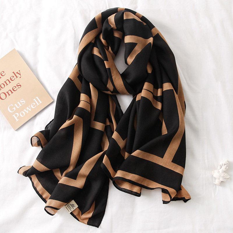 Black silk scarf with tan geometric blocks and soft drape, fringed edges.