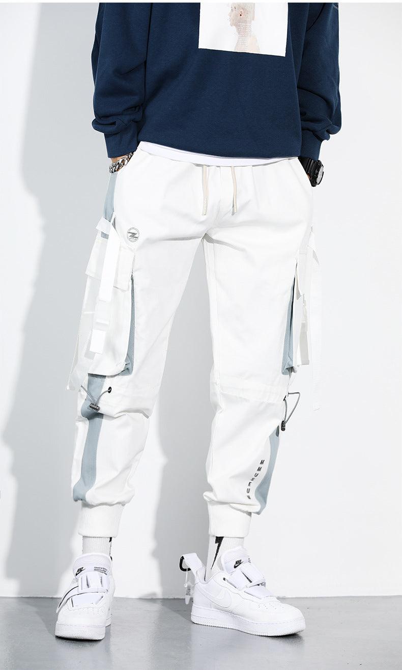 White harem cargo pants with drawstring cuffs, multi-pocket panels, and hanging straps