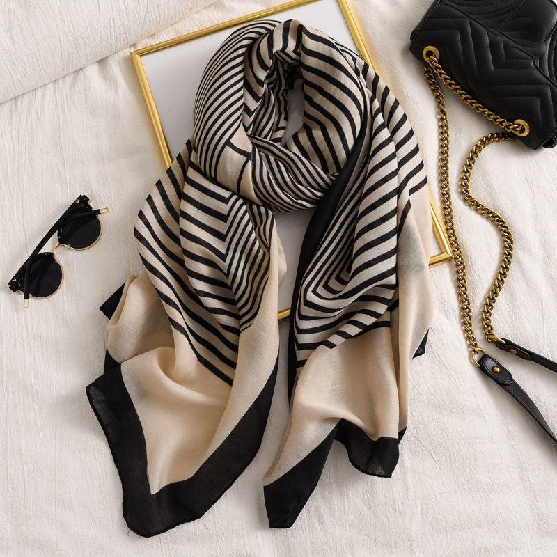 Long scarf with black and beige geometric stripe pattern, folded with soft drape