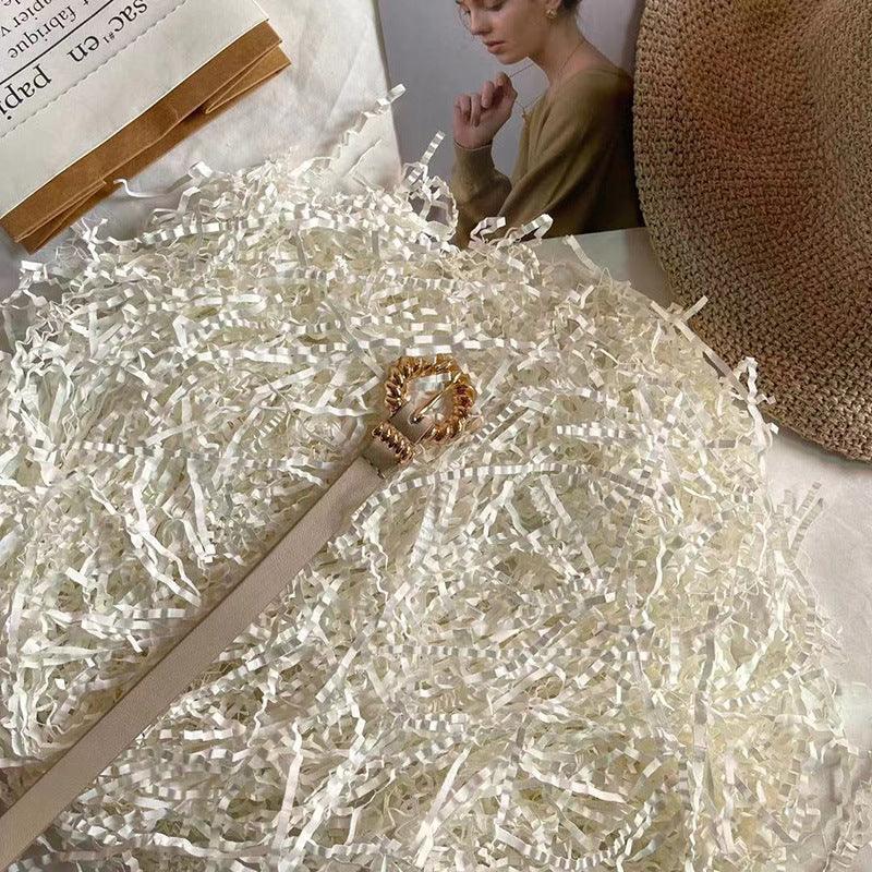Tan thin belt with gold-toned ornate buckle and decorative chain links