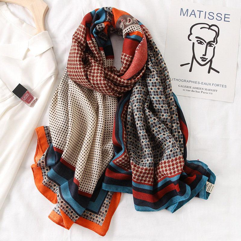 Silk scarf with orange, navy, and patterned dots and borders, neatly draped