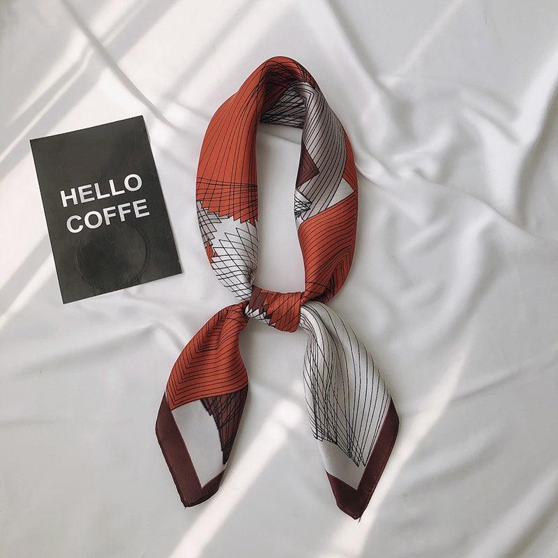 Printed scarf in rust red and gray with abstract grid pattern, tied bow with tails