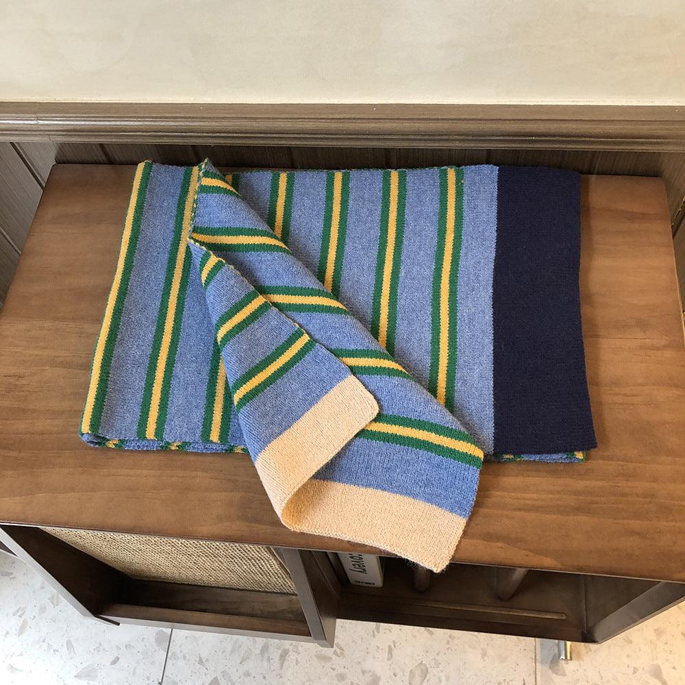 Knitted wool scarf folded; blue base with green and yellow stripe accents and cream end
