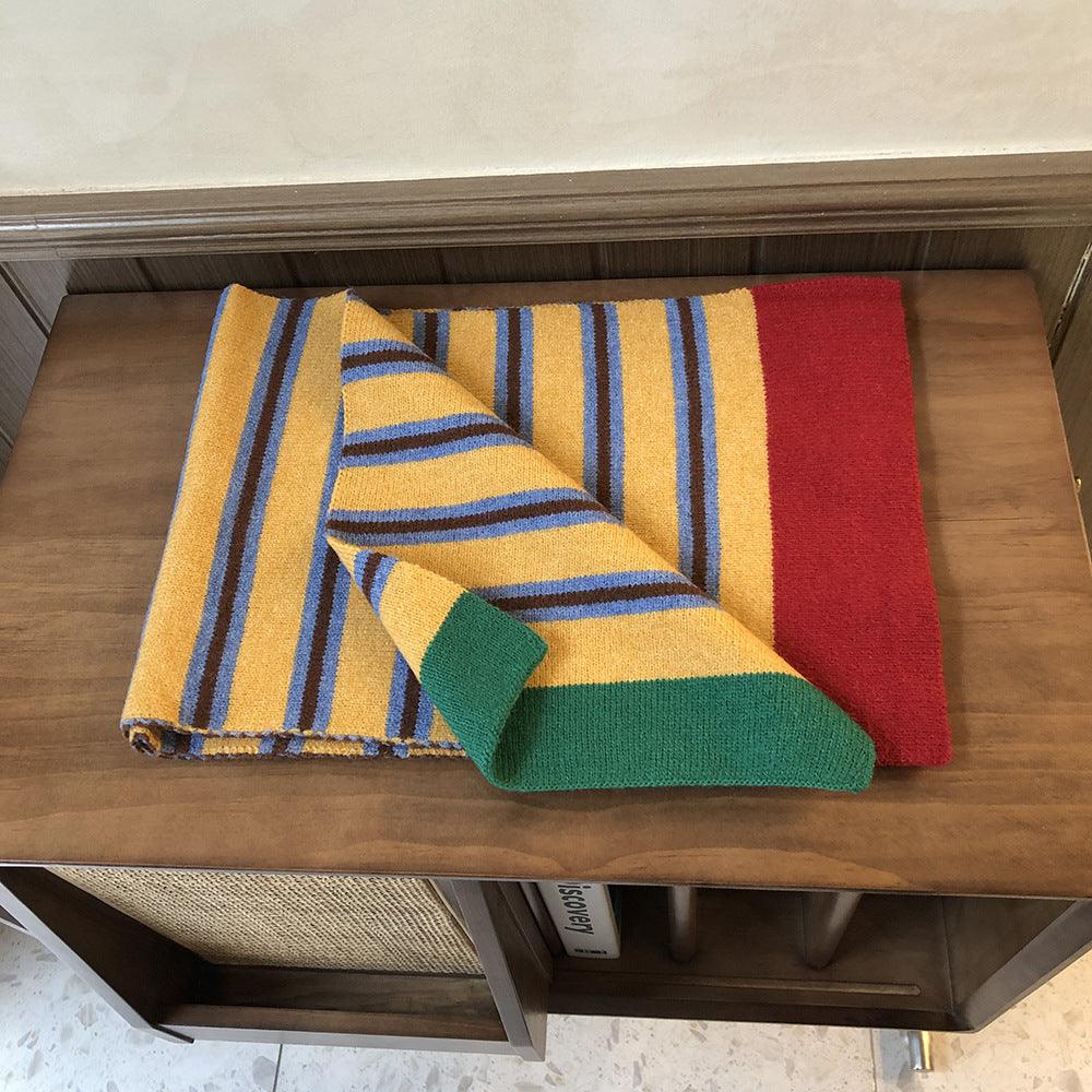 Knitted wool scarf folded on a table; yellow, blue stripe, and red panel design