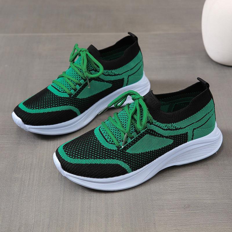 Green and black athletic sneakers with textured knit upper, green laces, white sole.