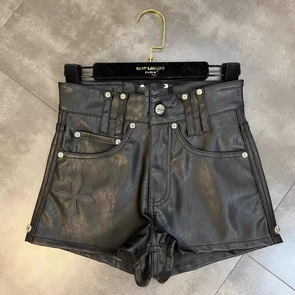 Black faux leather high-waist shorts with studded pockets and cross applique