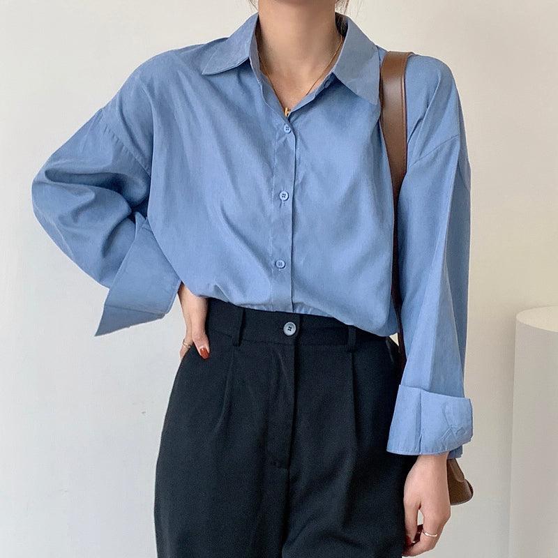 Women's light blue button-up shirt with pointed collar and long sleeves, worn with bag