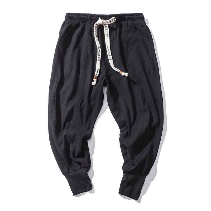 Men's black cotton drawstring pants with gathered waistband and tapered legs
