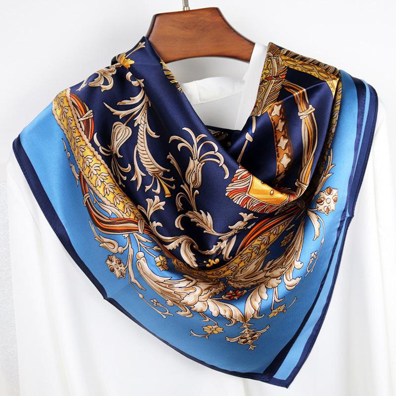 Navy silk scarf with gold and light-blue scroll pattern, neatly folded on a hanger