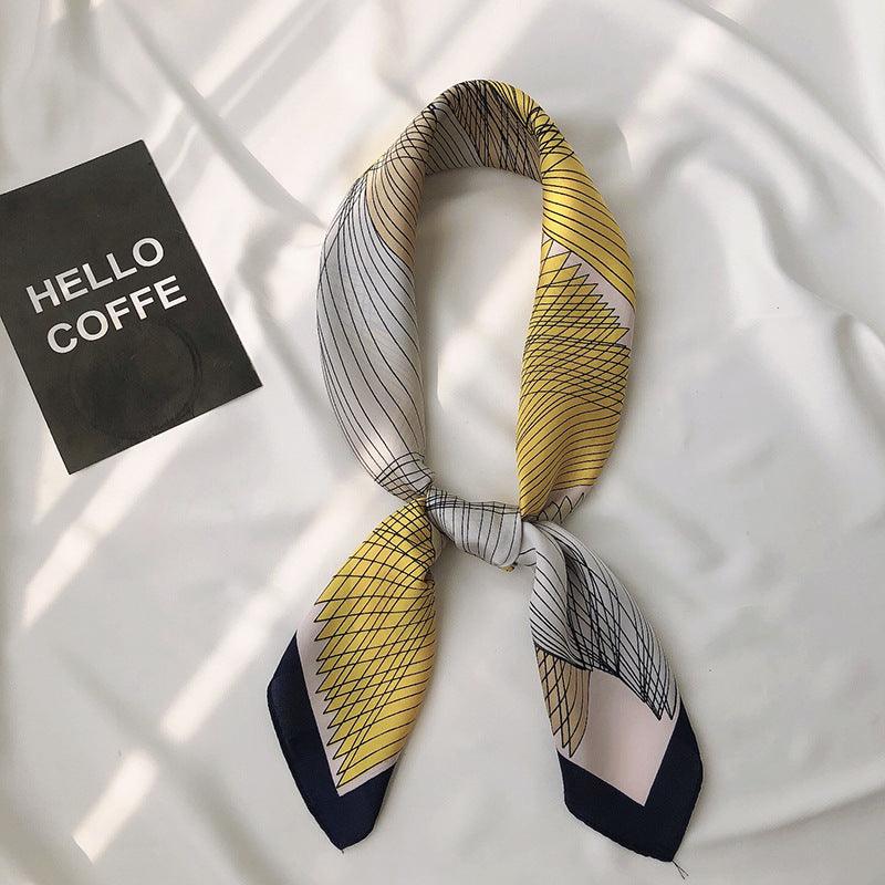 Printed scarf with yellow, navy, and white geometric grid lines, tied in a bow