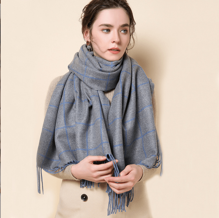 Warm cashmere scarf in grey with blue grid pattern and fringed ends.