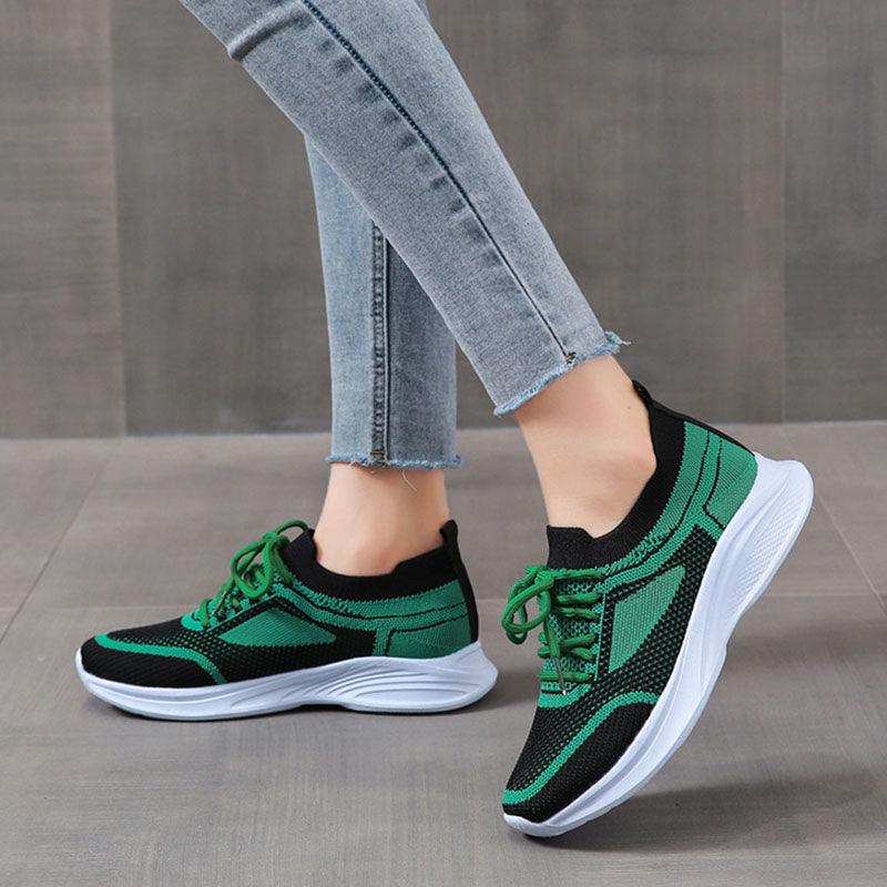 Green and black sports sneakers, green laces, white sole; worn with jeans.