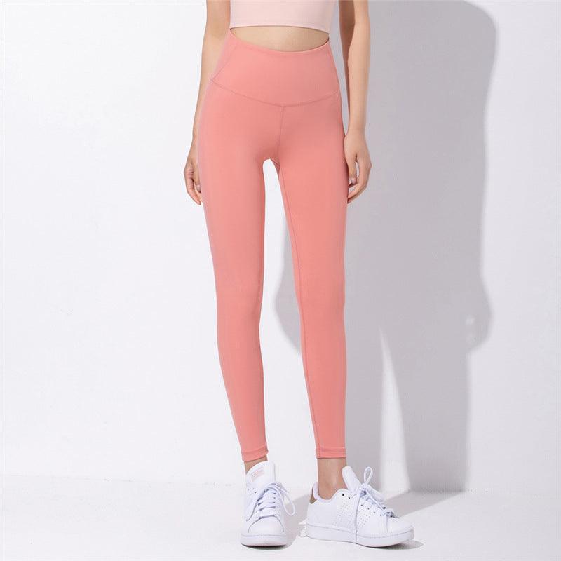 Coral pink high-waist yoga pants with back seam and fitted ankle-length legs.